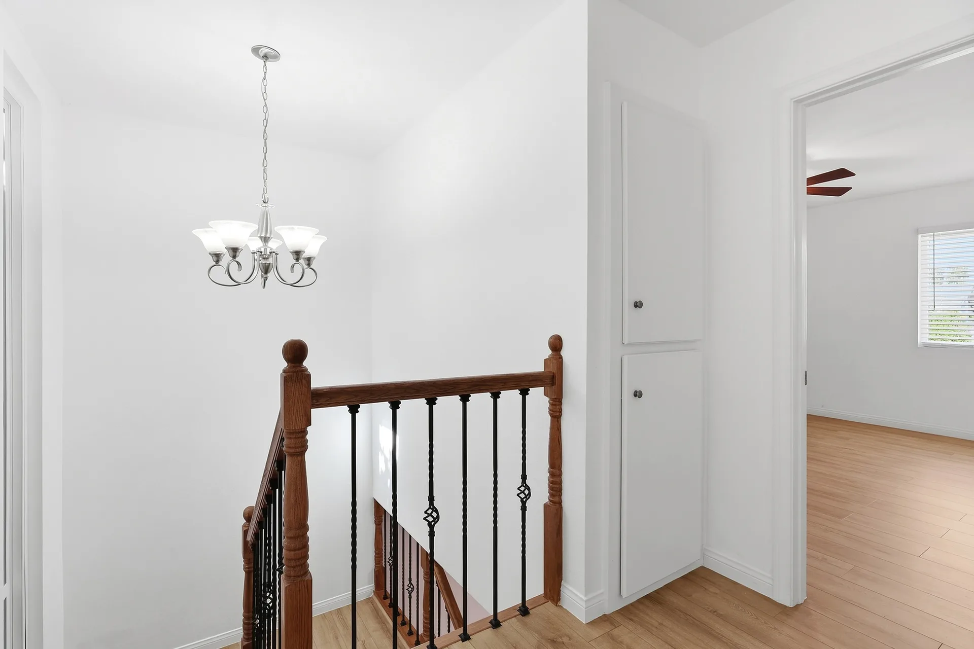 Staircase landing at 8 Silverwood with wood flooring, white walls, and a chandelier