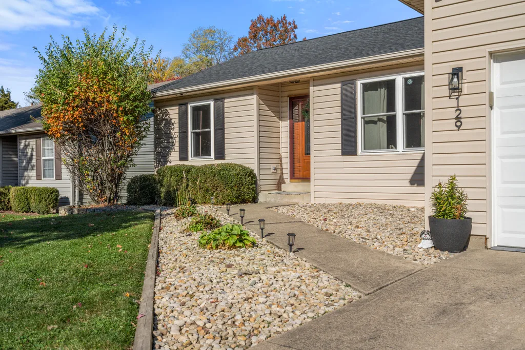 Ranch home facade with black shutters, rock garden and concrete walkway