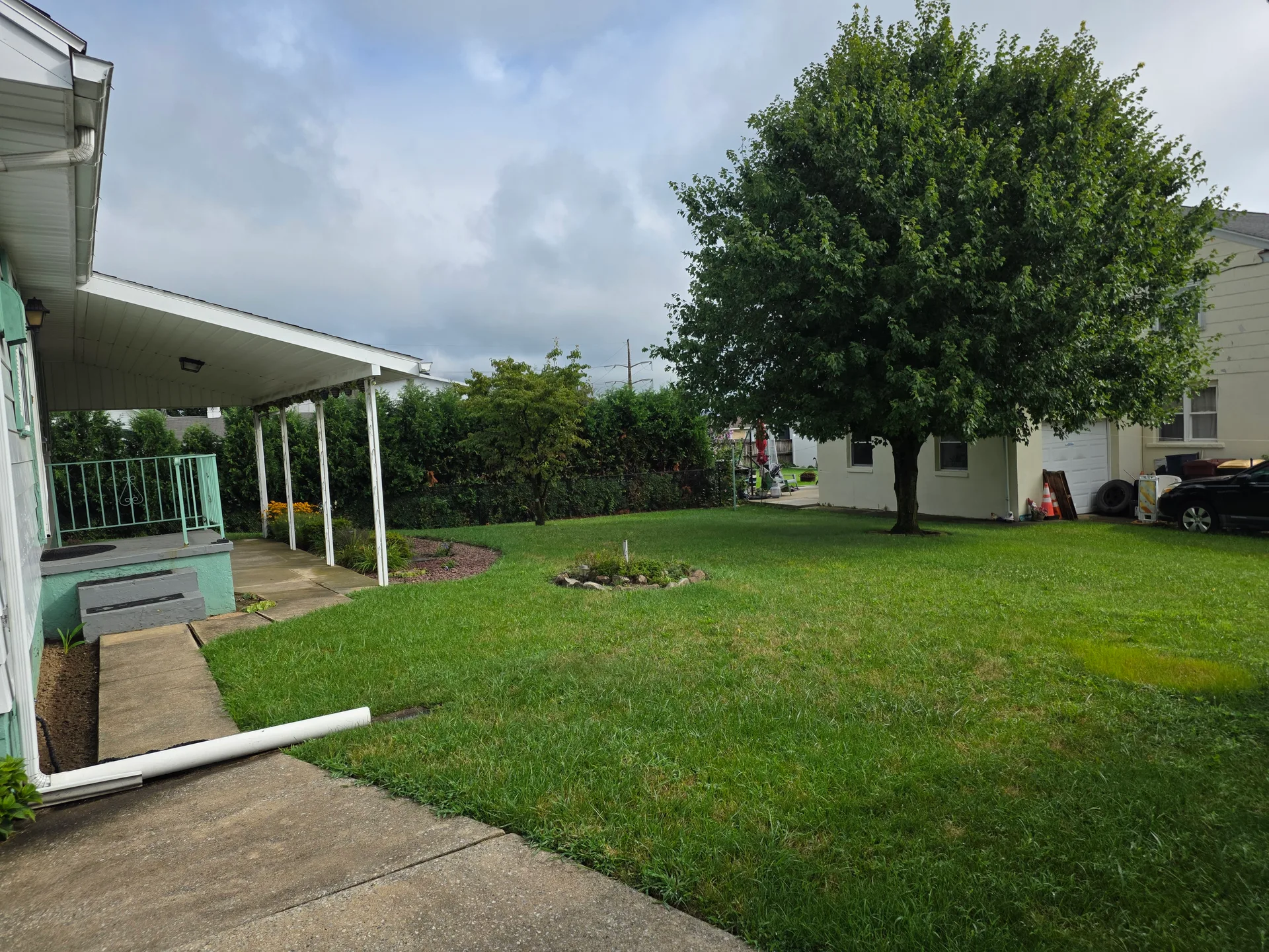 Covered concrete patio and backyard with stone garden bed
