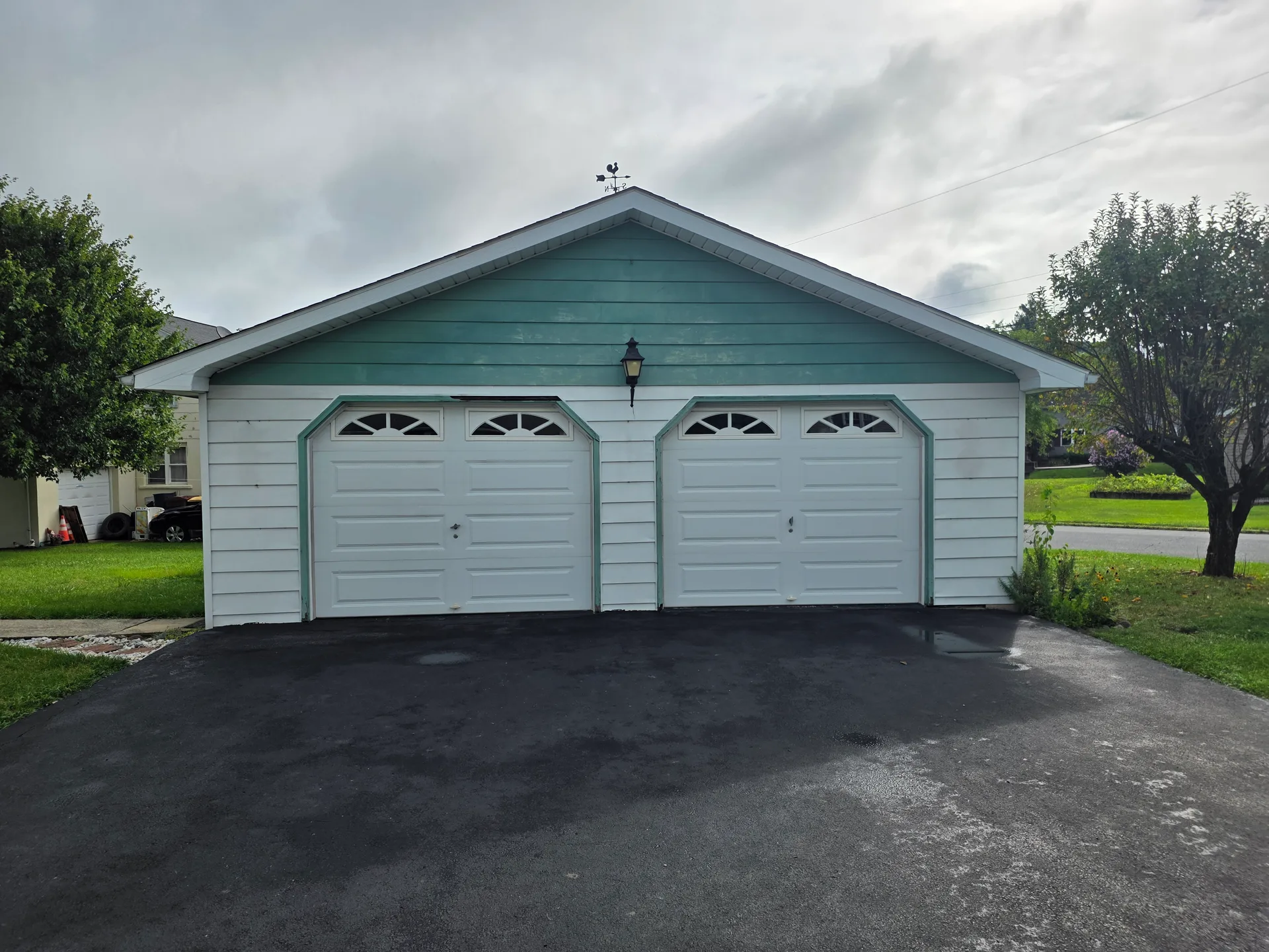 Detached two-car garage with teal gable end and weathervane