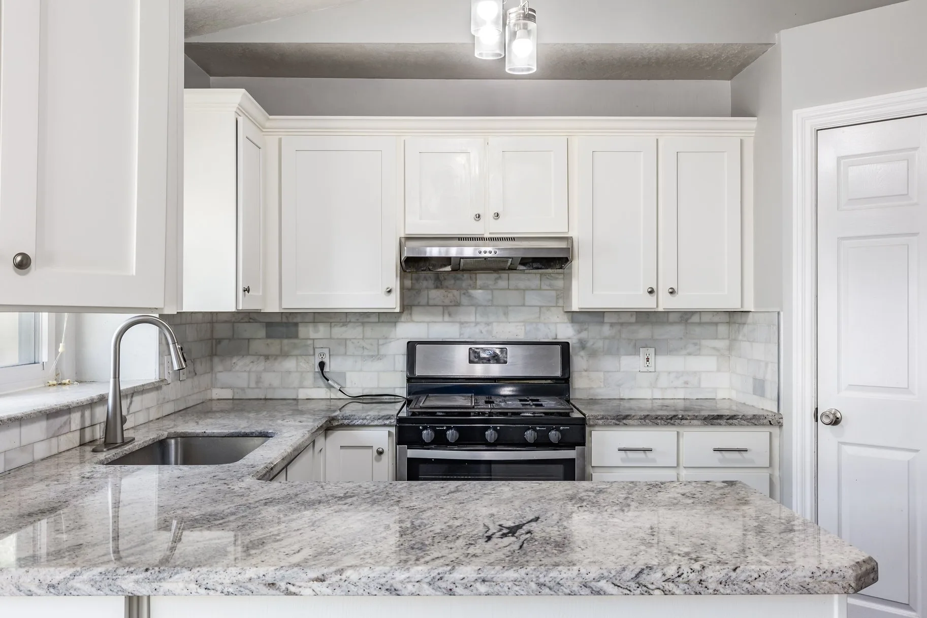 Updated kitchen with white cabinetry, granite countertops, and stainless steel appliances