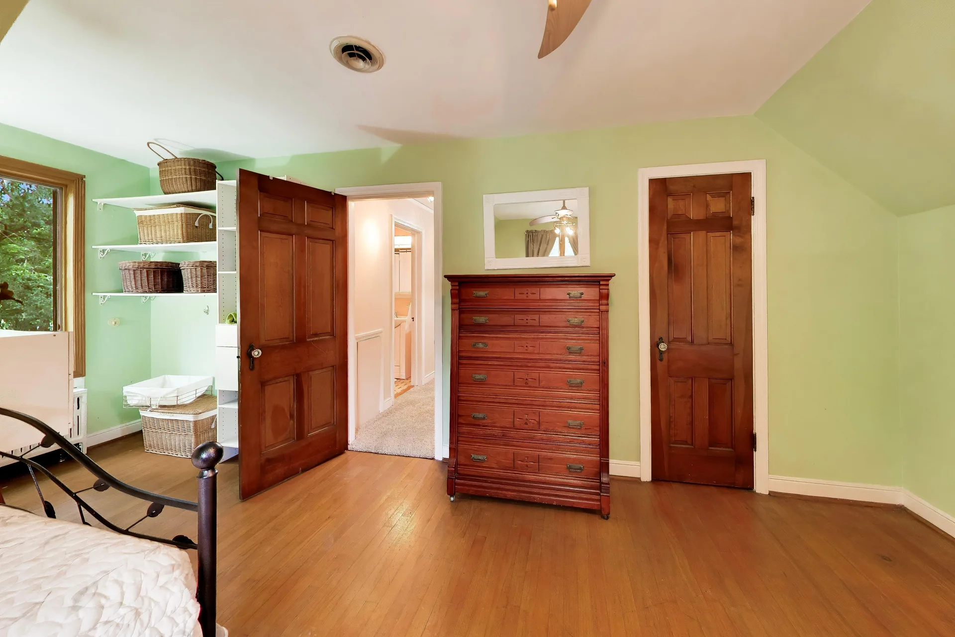 Bedroom with light green walls and hardwood floors