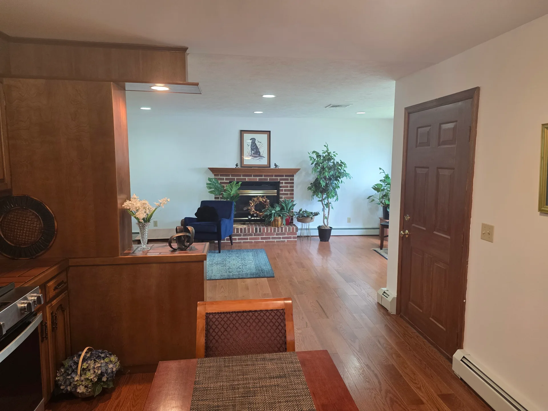 Open view from kitchen into living room with brick fireplace