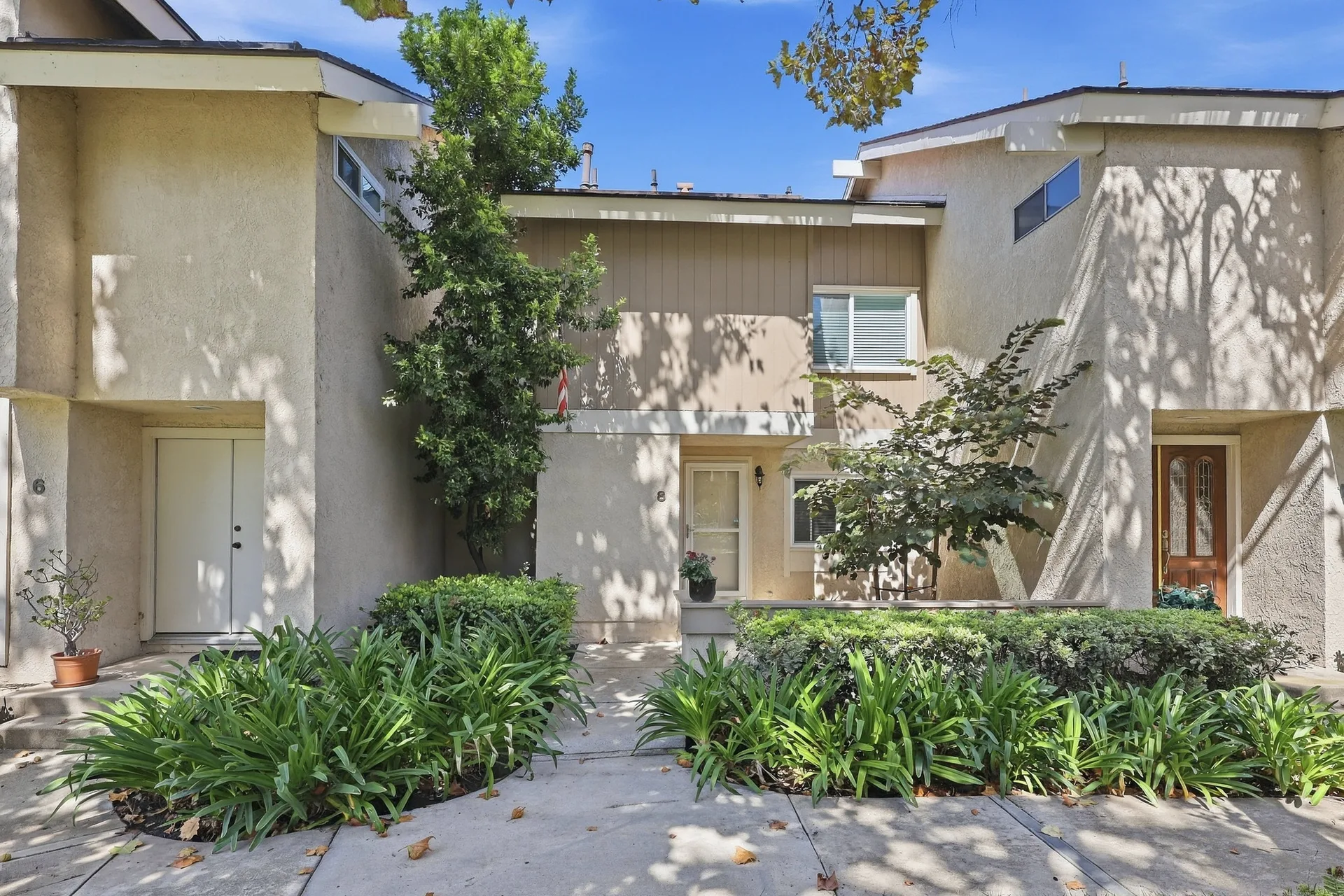 Exterior entrance of 8 Silverwood with a paved walkway, stucco facade, and established landscaping