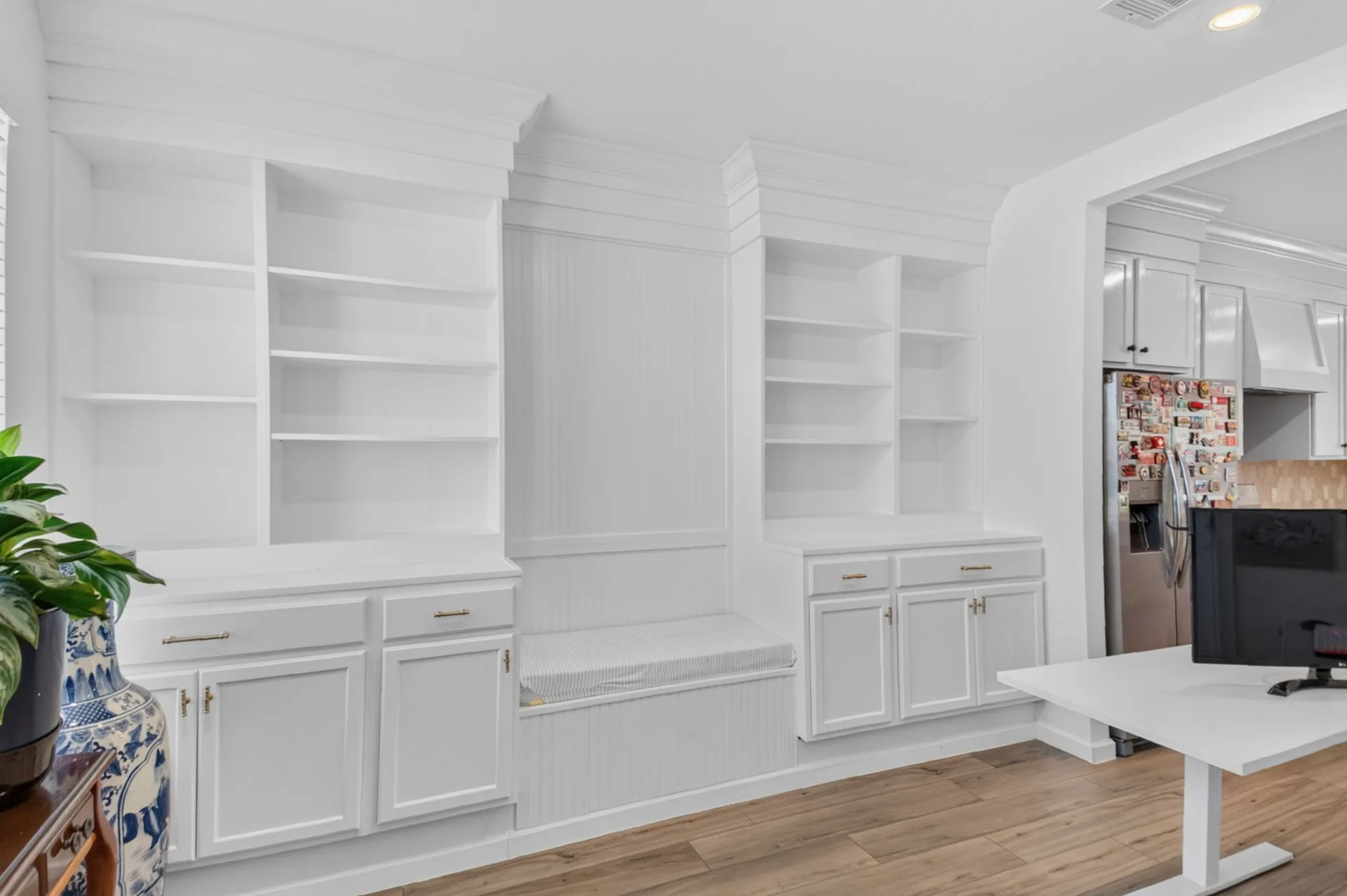 Wall of built-in living-room cabinetry in crisp white with light wood flooring