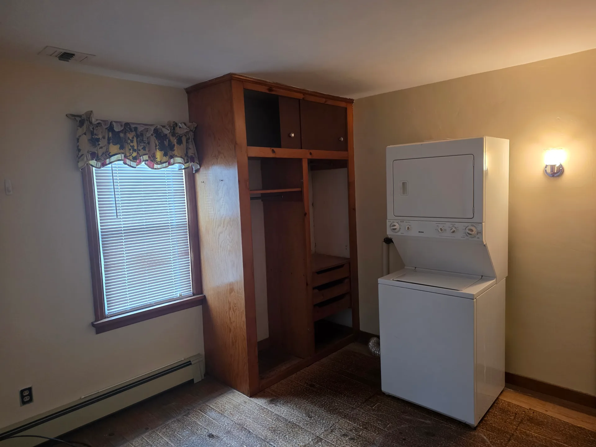 Room repurposed for laundry with stackable washer/dryer and built-in wardrobe cabinet