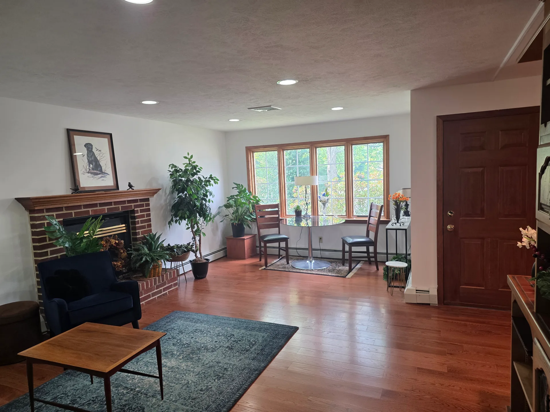 Living room with brick fireplace and large windows with wood trim
