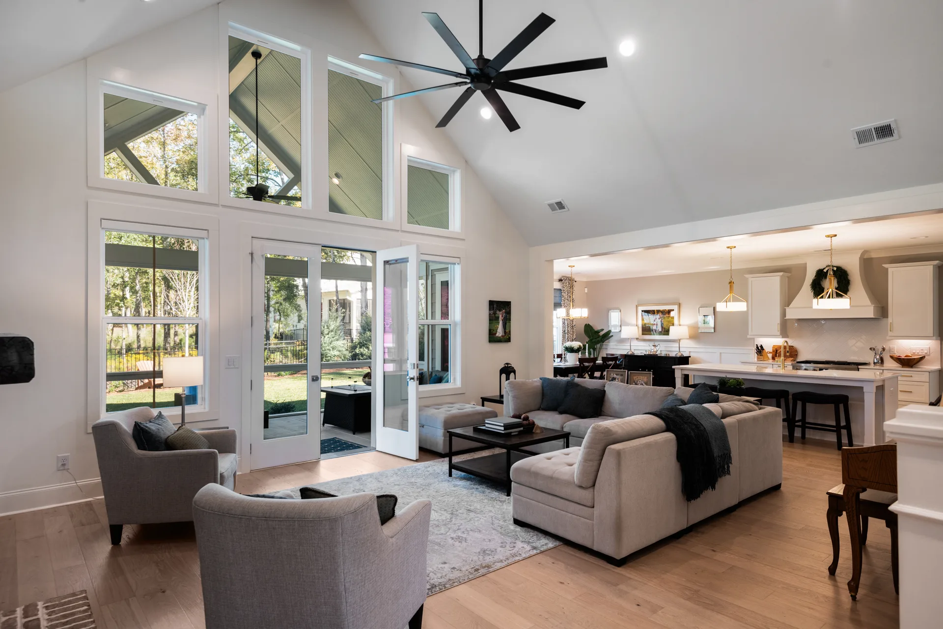 Great room open to the kitchen, with tall windows and hardwood floors