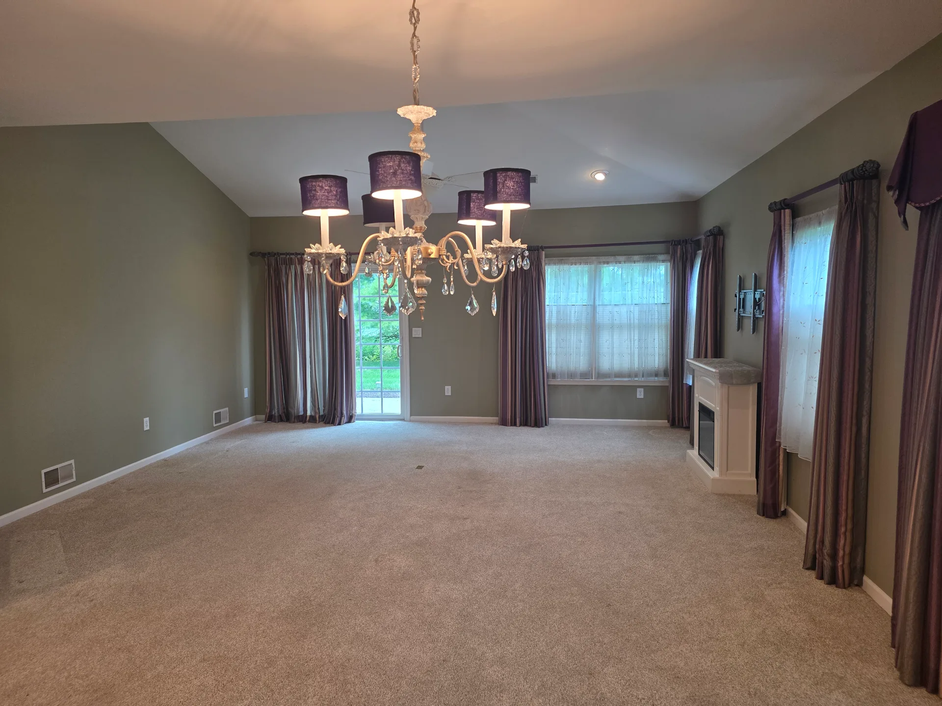 Vaulted living room with neutral carpeting and a chandelier