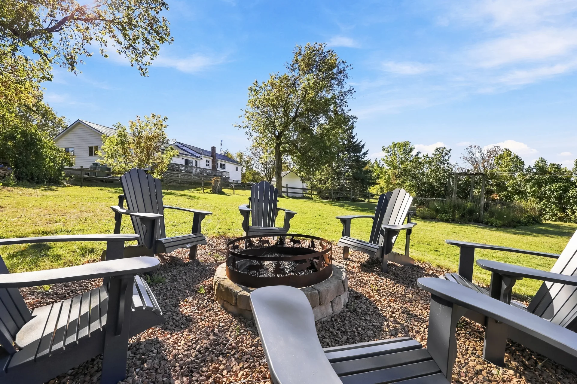 Adirondack chairs around the stone fire pit on the back lawn