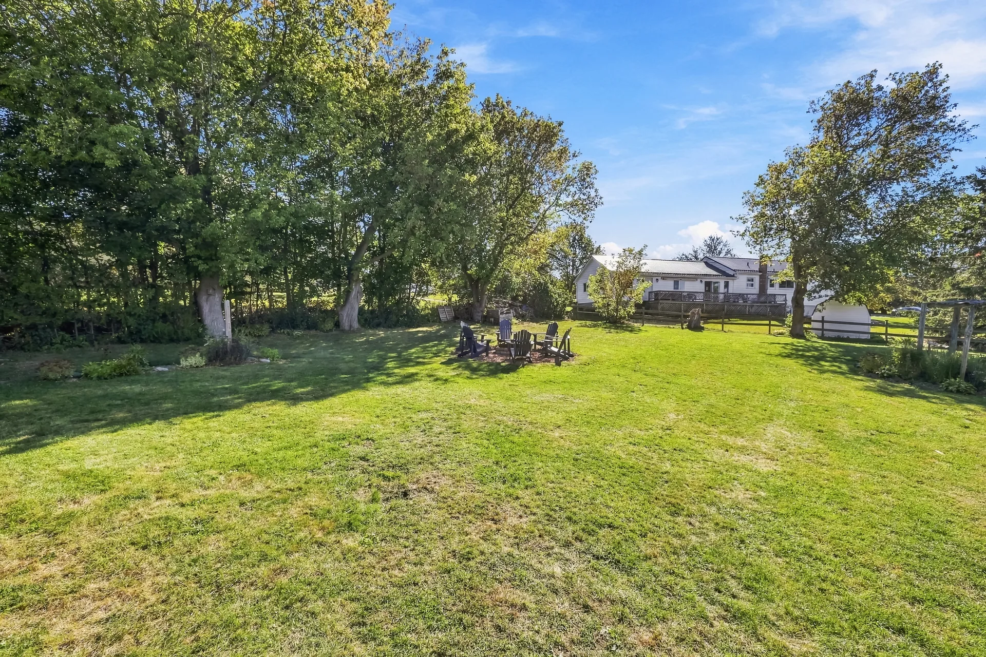 Spacious rural backyard with mature trees and a fire pit area