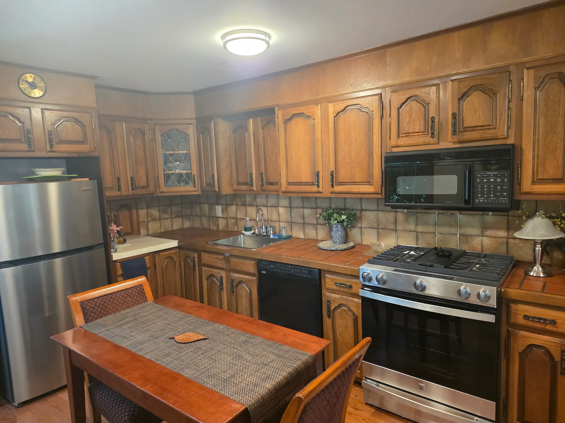 Kitchen with traditional wood cabinetry, tiled countertops, and stainless steel appliances