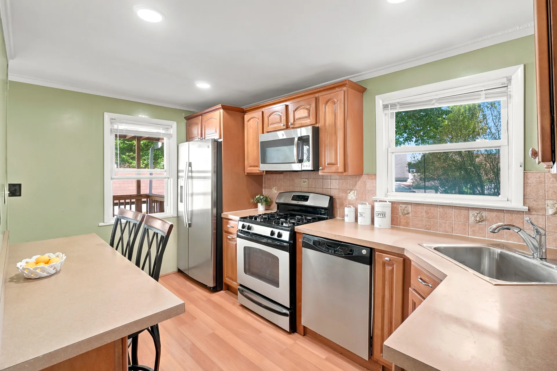 Kitchen with light wood cabinetry, beige laminate counters, and daylight from two windows
