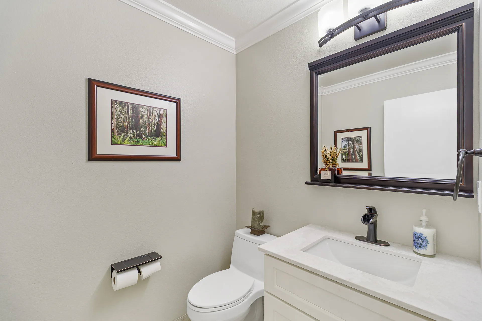 Powder room with white vanity, quartz countertop and dark framed mirror