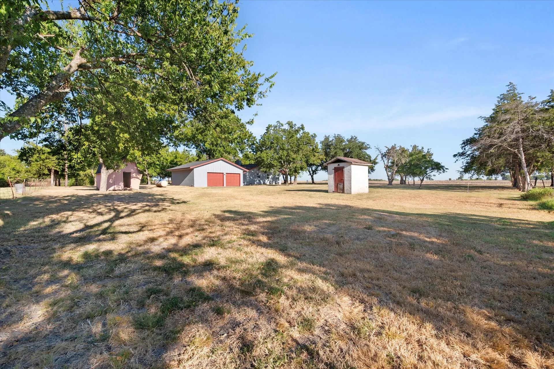 View across the pasture toward the detached garage and outbuildings
