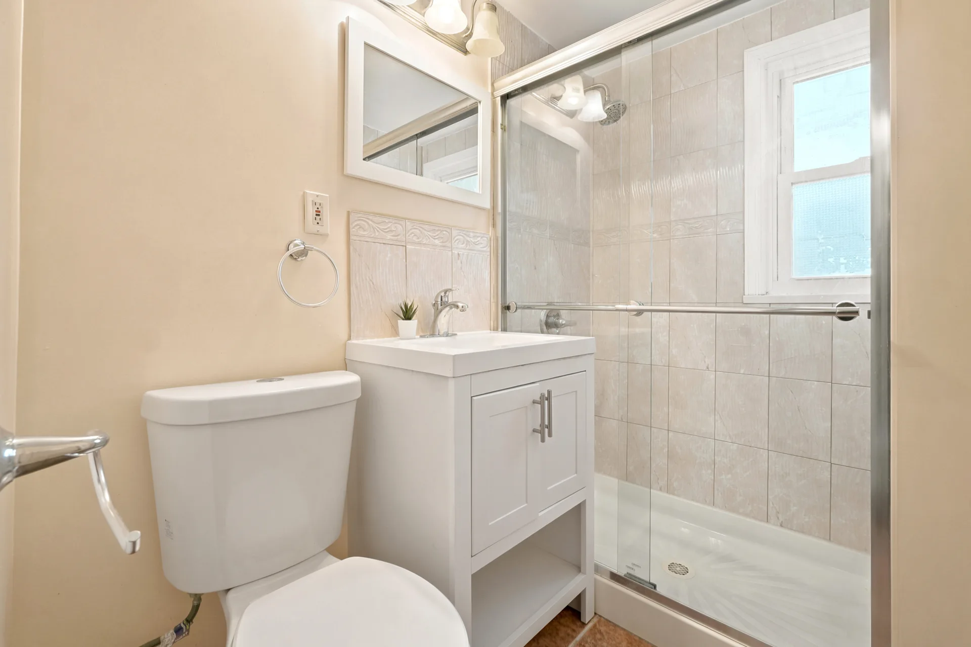 Renovated full bathroom with white vanity and glass-enclosed shower