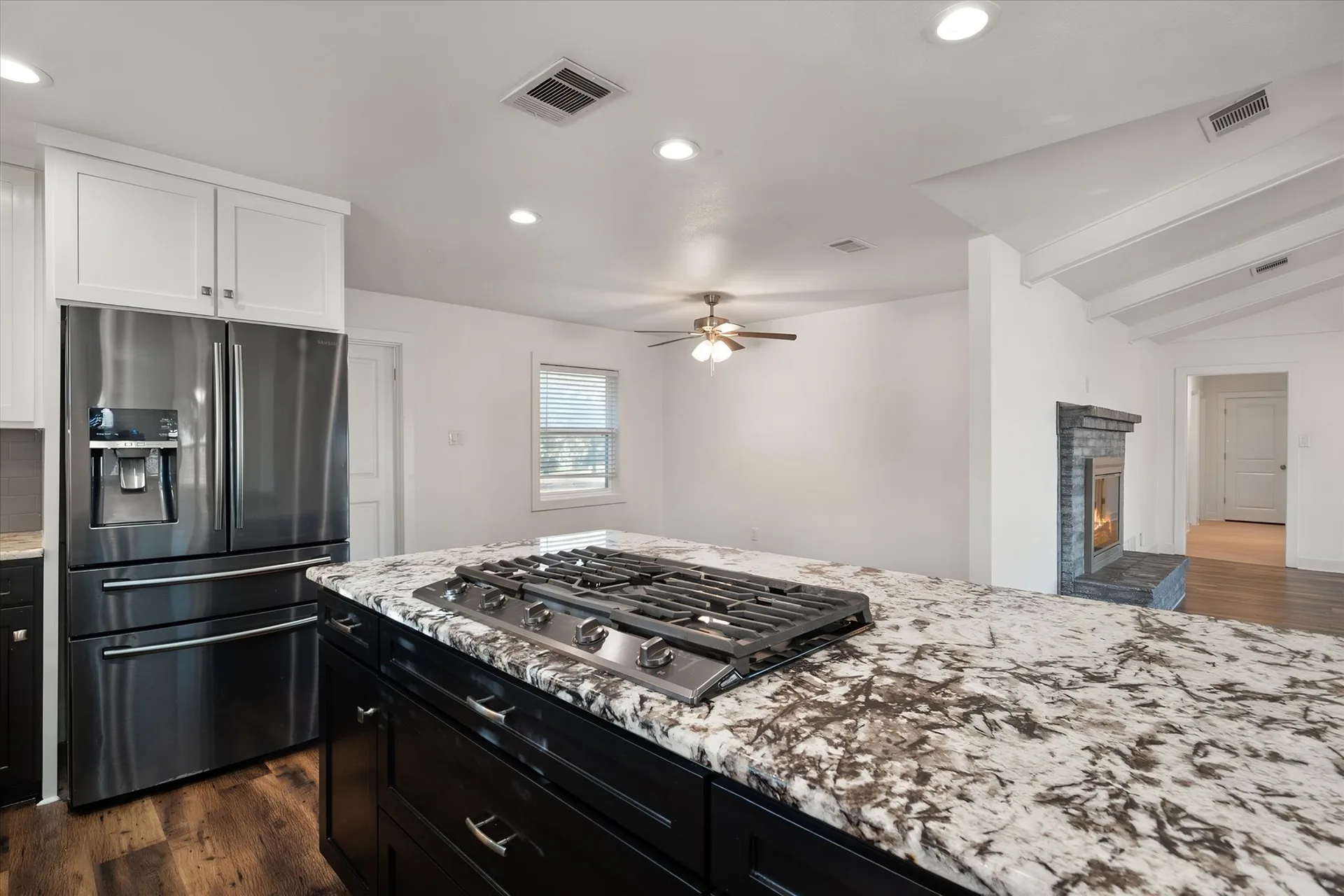 Kitchen with a black island, white granite counters and a stainless refrigerator