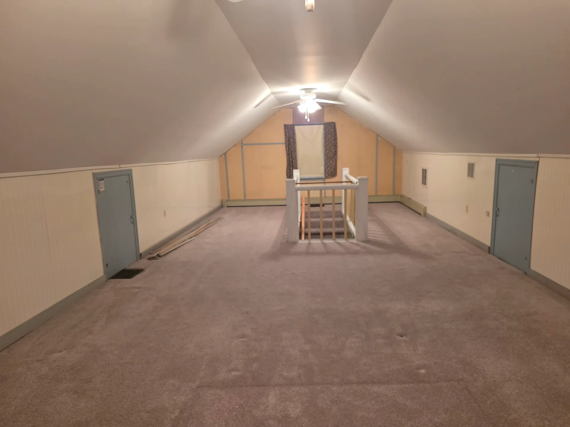 Upper-level bedroom with vaulted ceilings, blue painted storage doors, and central staircase