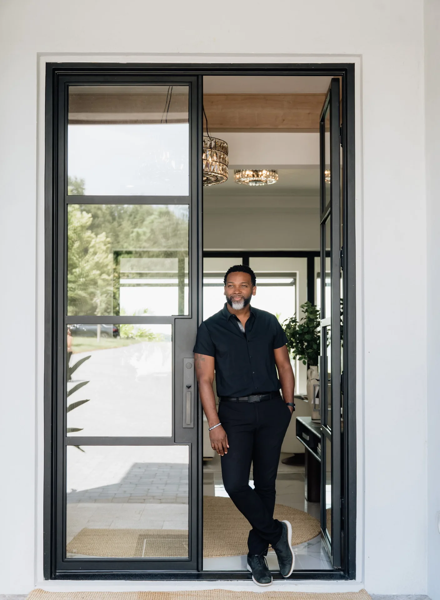 Mike Collier standing full-length in the doorway of a modern Southwest Orlando home, real estate agent with eXp Realty