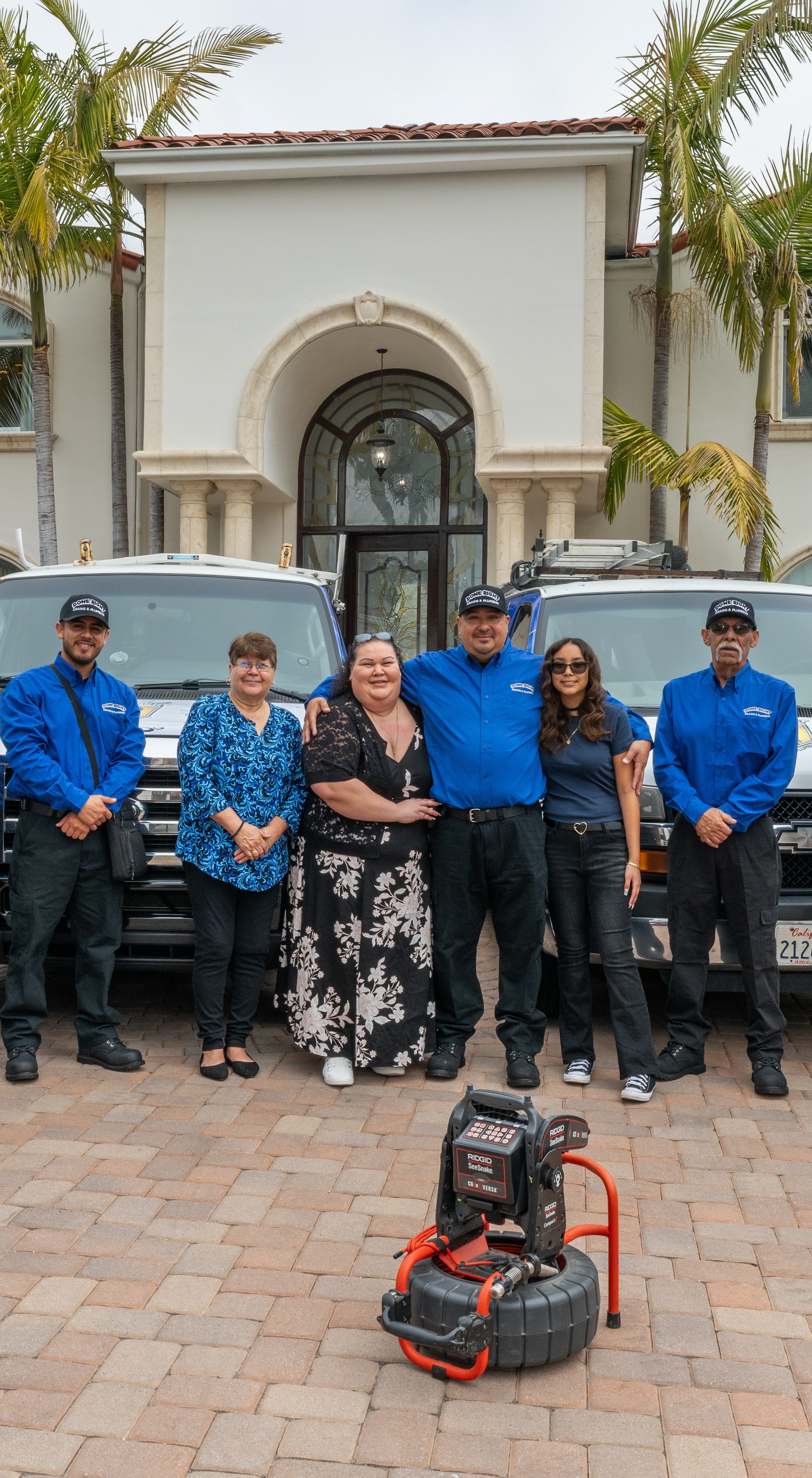 The Done Right Drains And Plumbing family standing together in front of their work trucks