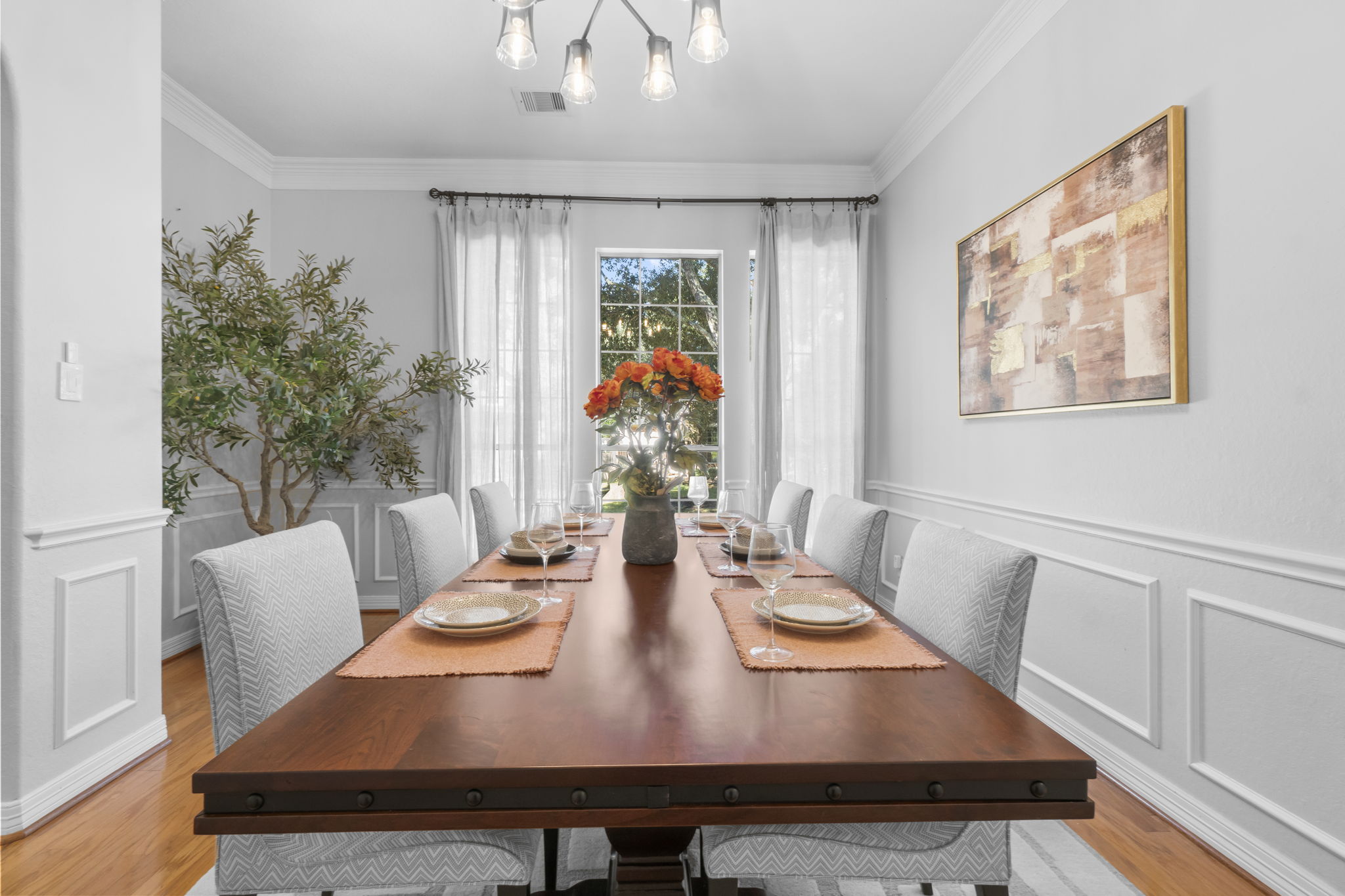 A dining room with wainscoting, staged and lit to show the home at its best