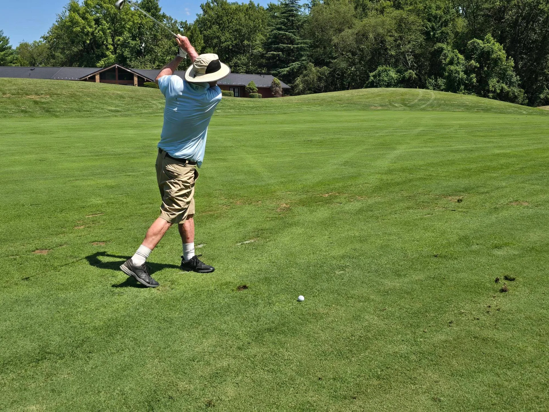 Golfer mid-swing on the fairway at the FORE the KIDS Golf Tournament