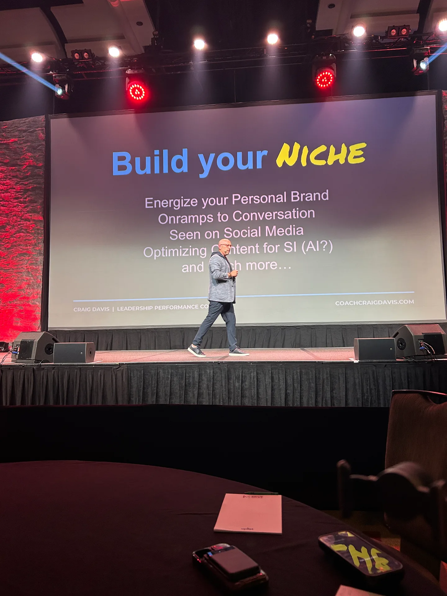 Craig Davis walking the stage in front of the Build Your Niche slide while delivering his keynote at Momentum Builder Live