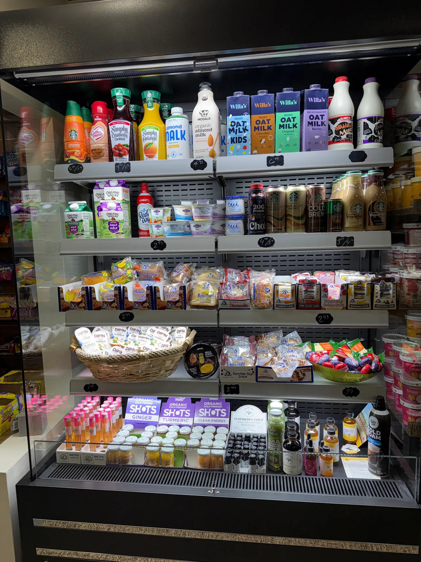 The refrigerated cold case at Beechside Goodies stocked with juices, oat milk, and coffee drinks