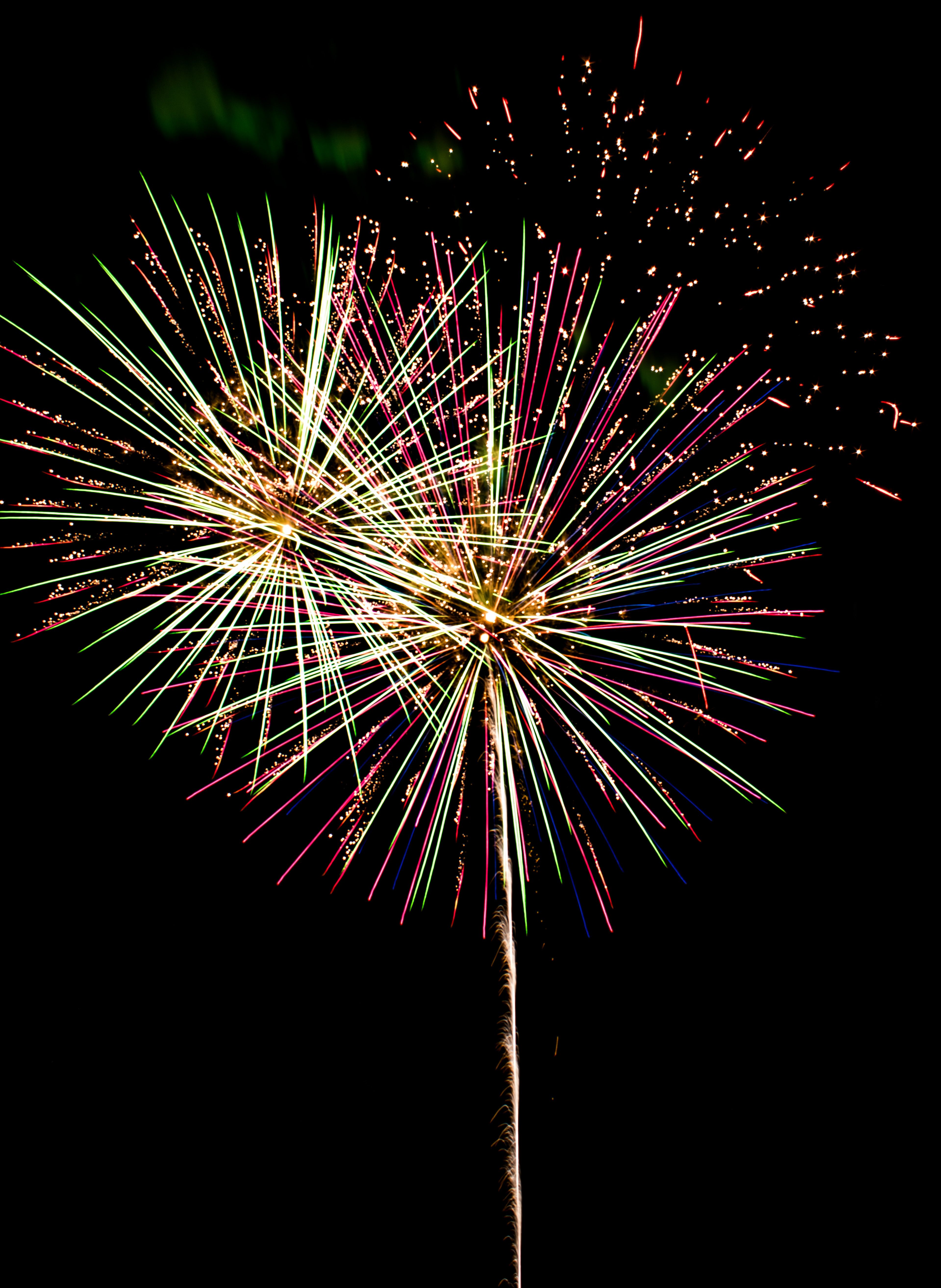 Vibrant neon fireworks in pink, magenta, electric blue, and lime green bursting across the night sky