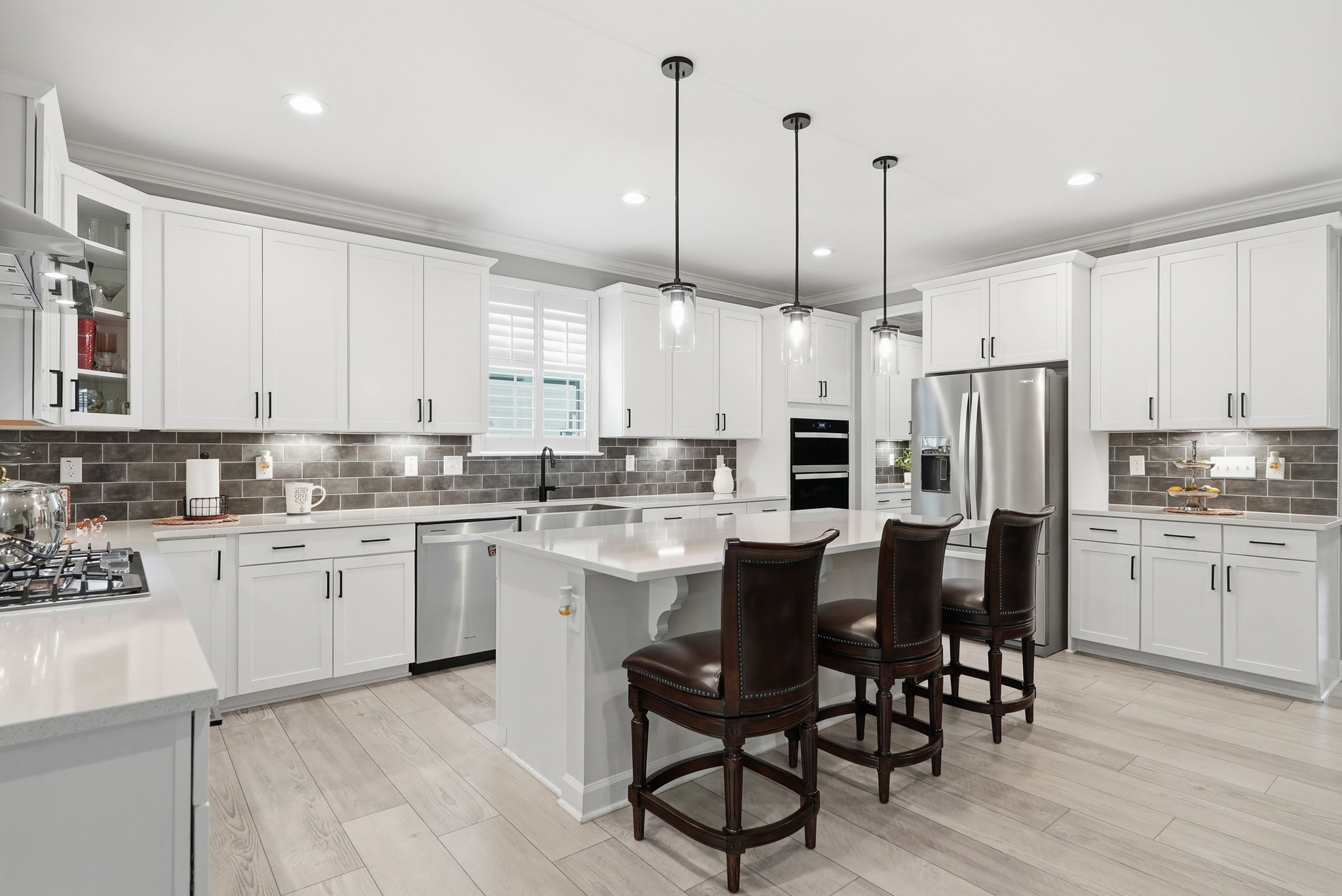 Chef's kitchen with white shaker cabinets, quartz countertops, and a large center island