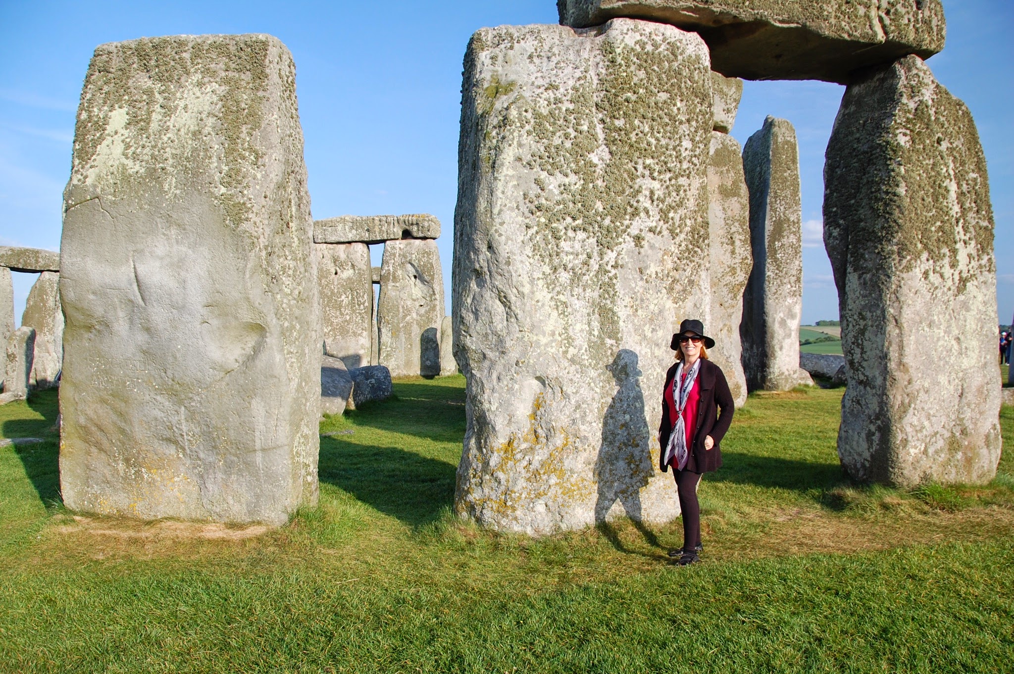 Carol standing among the large stones at Stonehenge, wearing a hat and scarf.