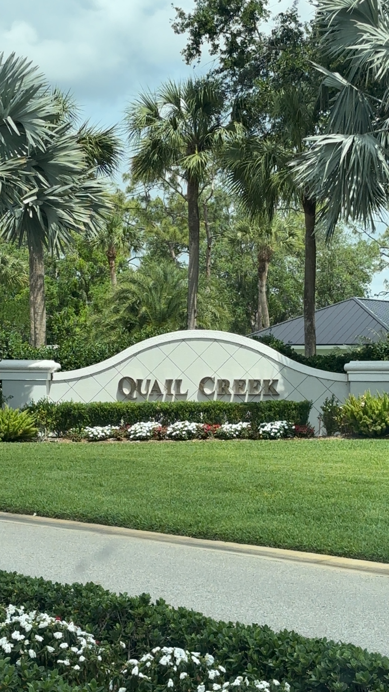 Quail Creek Country Club entrance monument sign with lush tropical landscaping and palm trees in Naples, Florida