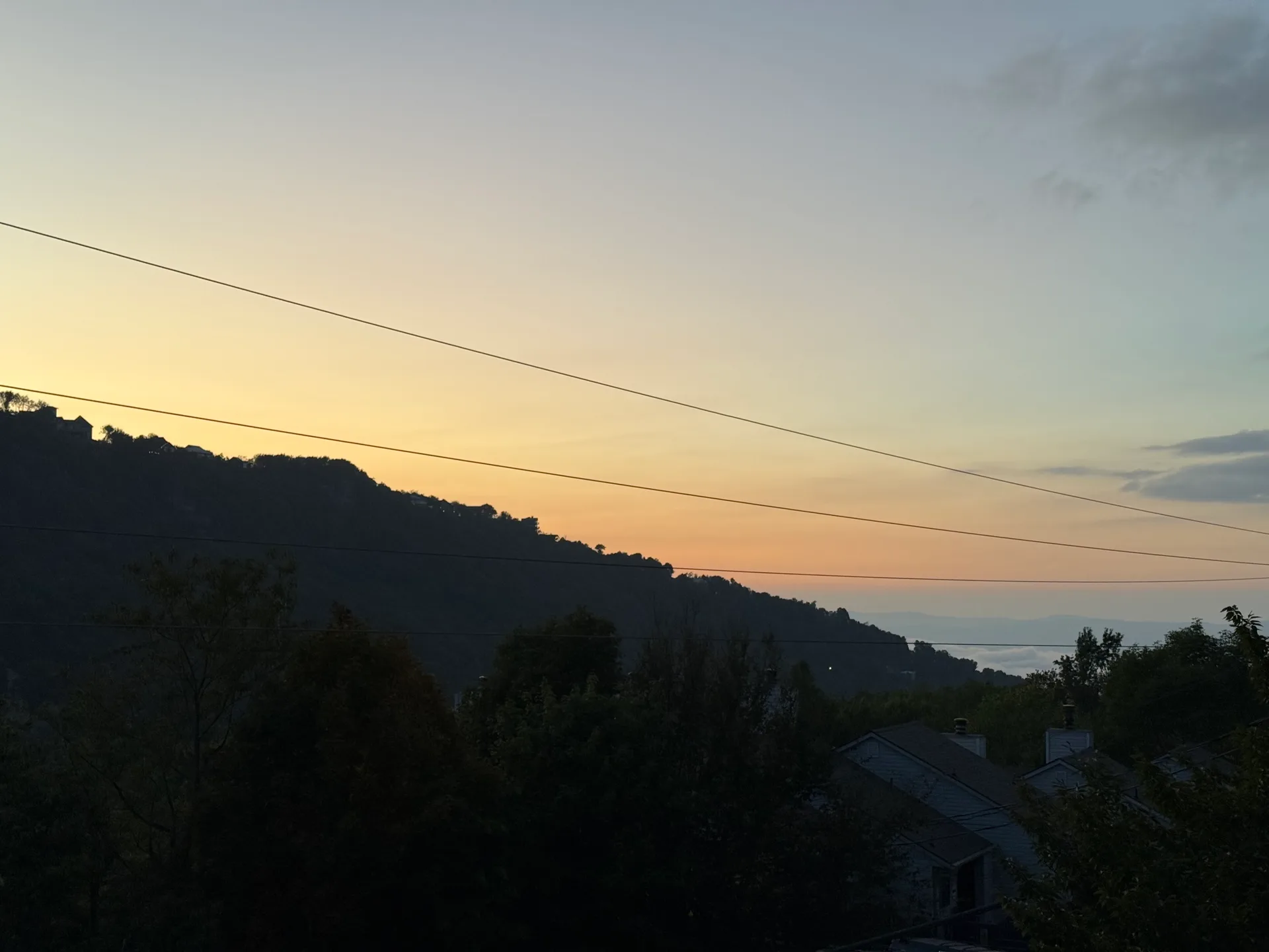 Silhouette of the mountain range against a warm gradient sunset sky, seen from the cabin's back porch