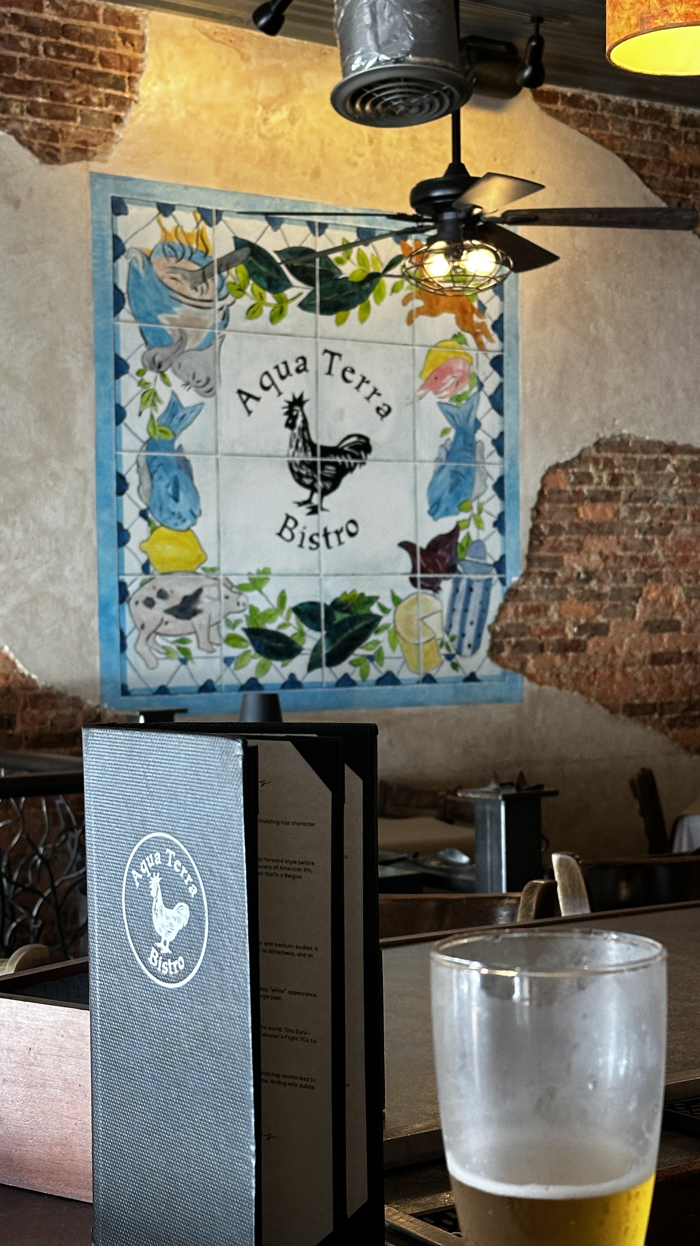 Aqua Terra Bistro dining room with exposed brick walls and signature rooster logo in Buford Georgia