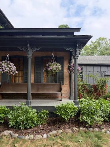 A brick house front porch with hanging flower baskets