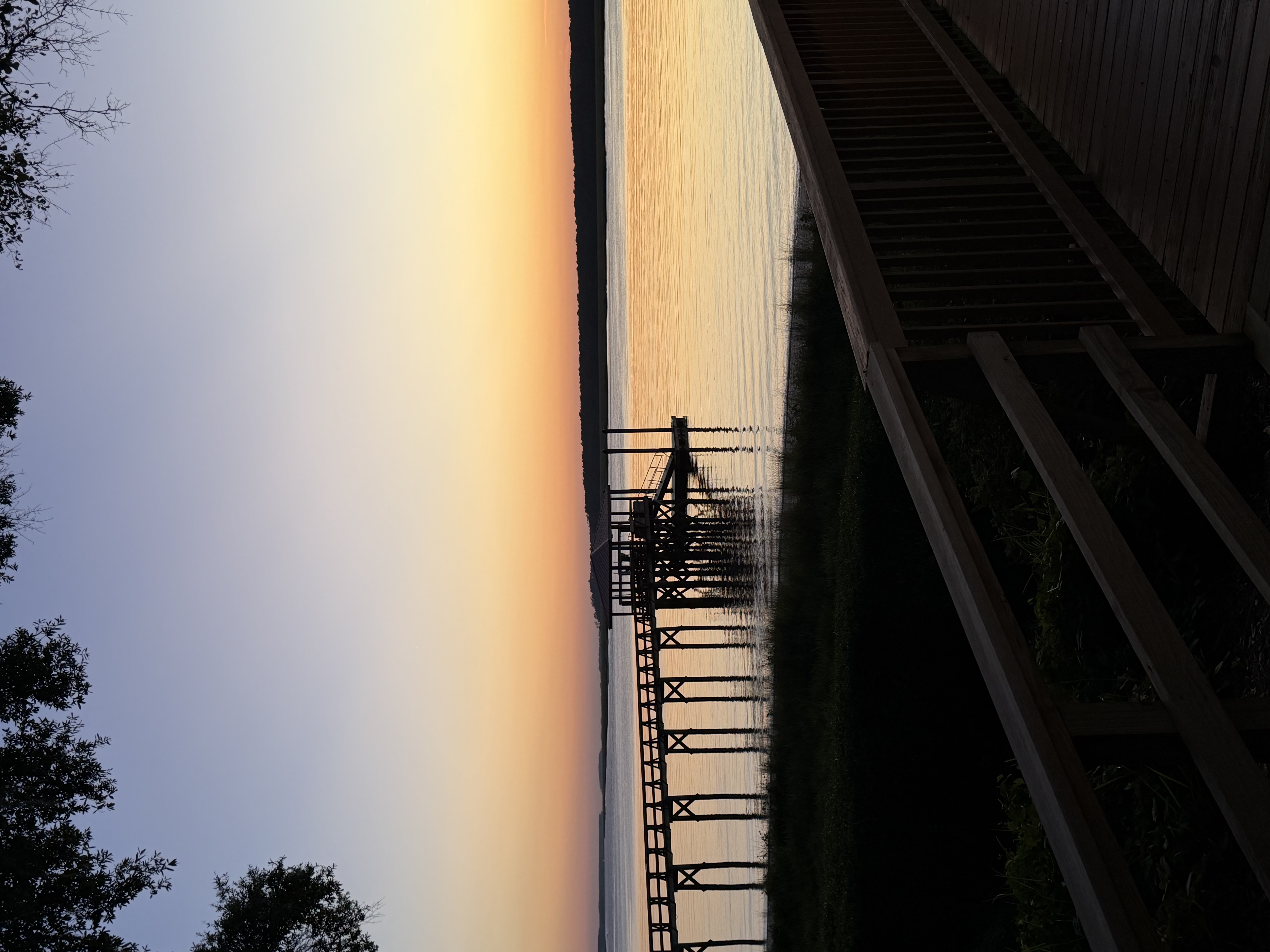 Long wooden pier reaching into calm water at sunset