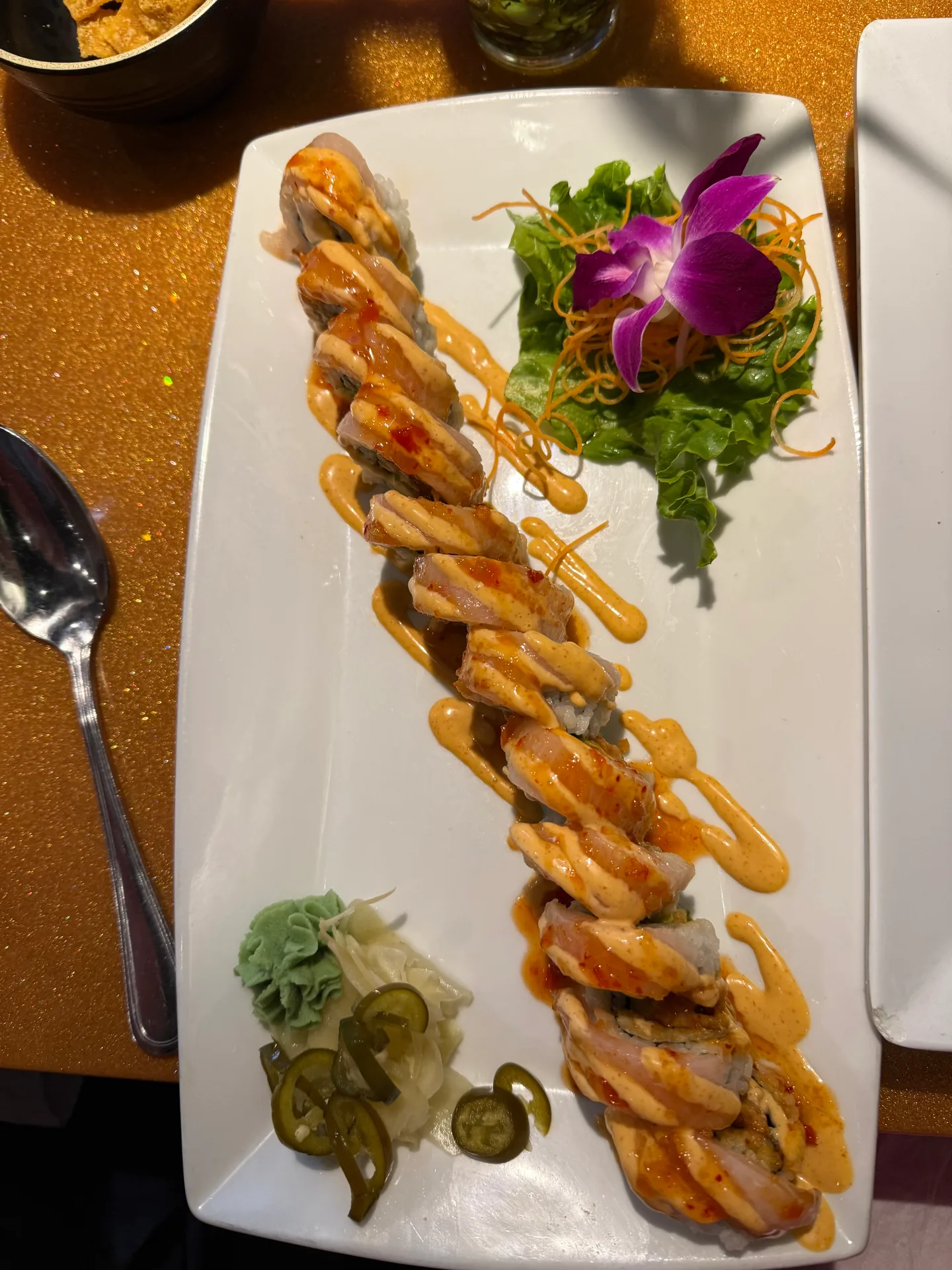 A sushi roll with a creamy reddish-orange sauce and an orchid garnish at Nguyen's Asian Grill in Banner Elk