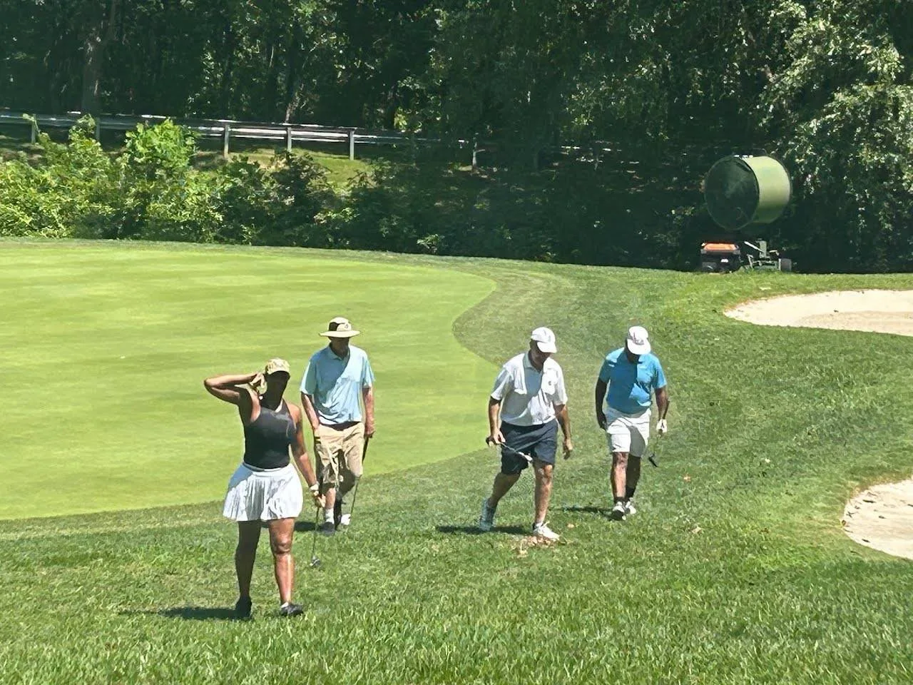 Golfers walking the fairway past the sand bunker at the FORE the KIDS Golf Tournament