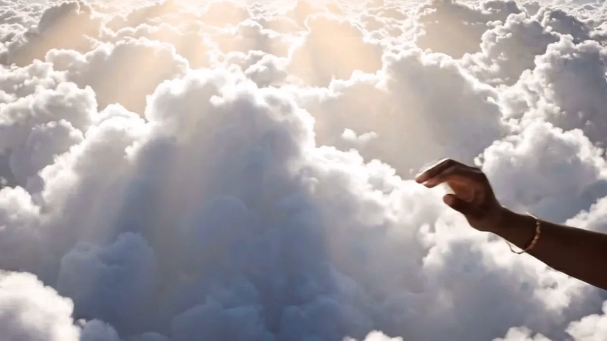 A hand reaching out over a sea of clouds with warm sunlight above Flagstaff