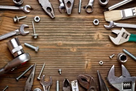Handyman tools arranged in a circle on rustic wood with an open center, the everyday toolkit of a handyman near me in San Antonio