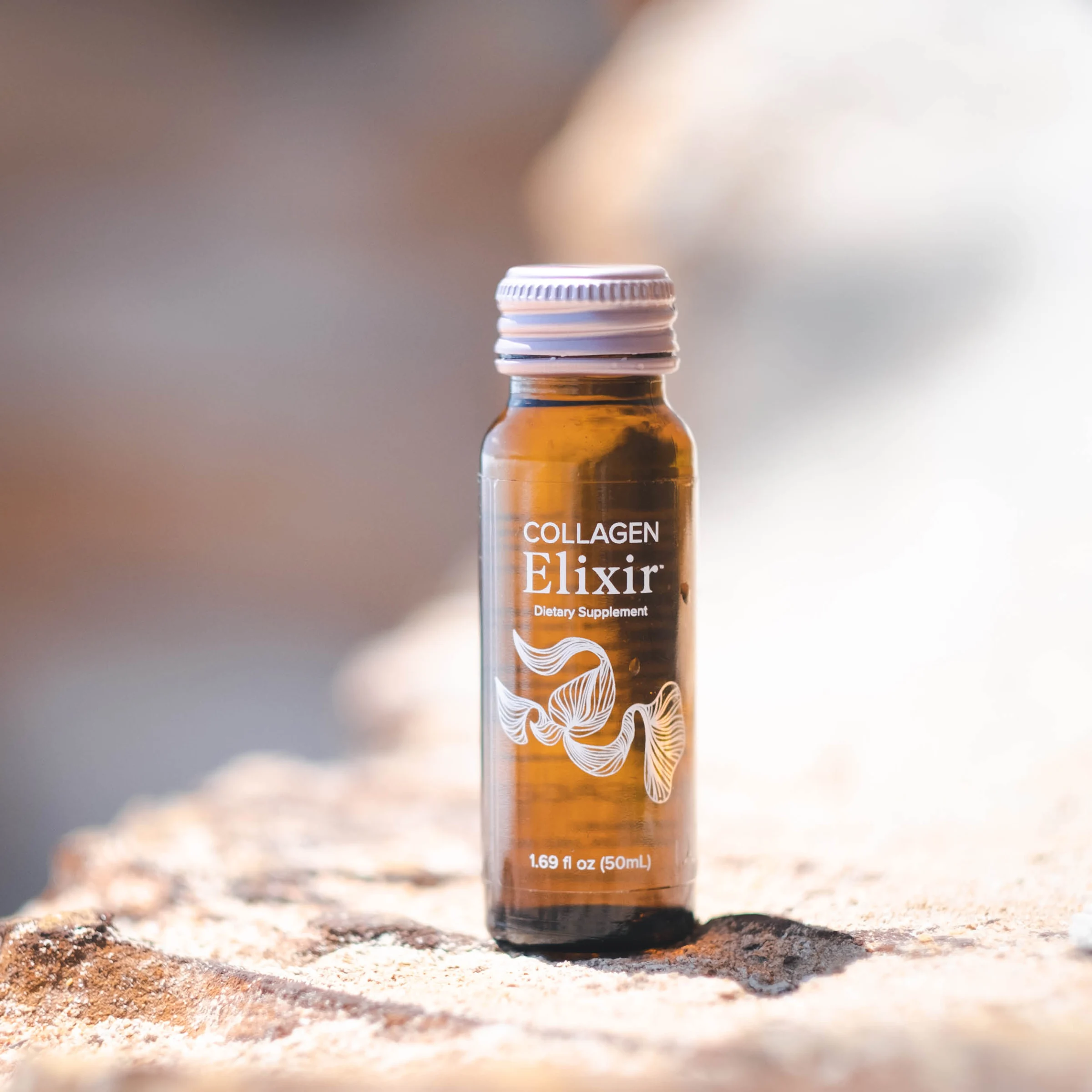 A bright, softly styled wellness photograph in blush pink and cream tones of the rose-pink Isagenix Collagen Elixir and a sweet pink sip