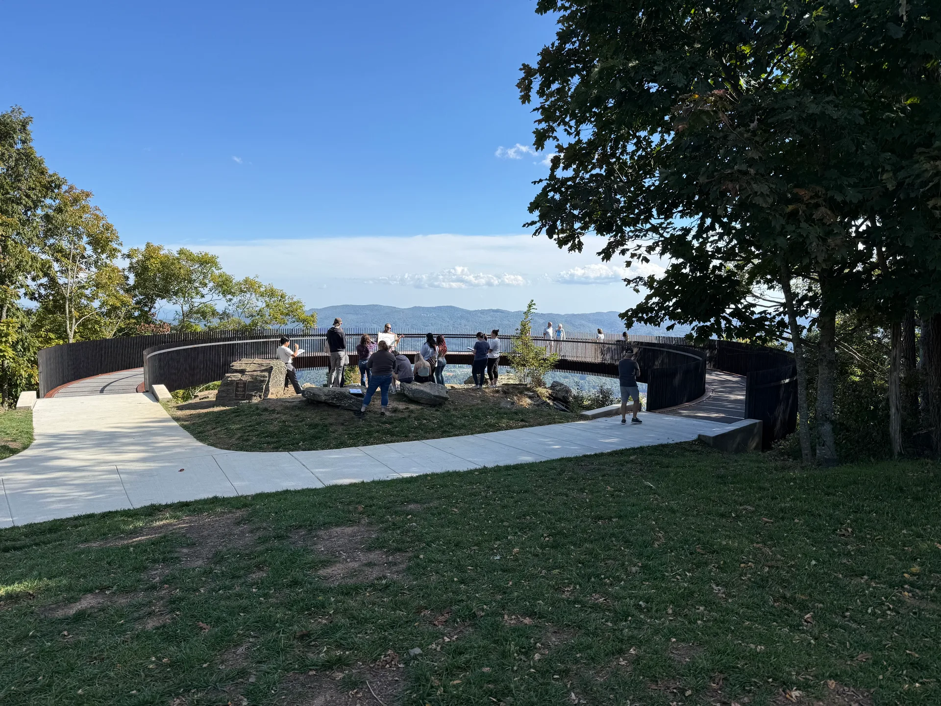 The paved circular overlook at the summit of Howard Knob with a metal railing and visitors taking in the view