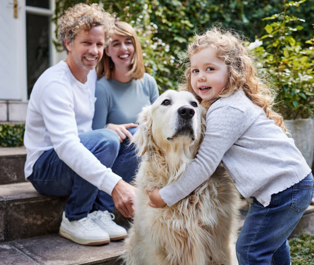A family gathered outside their home with their dog.
