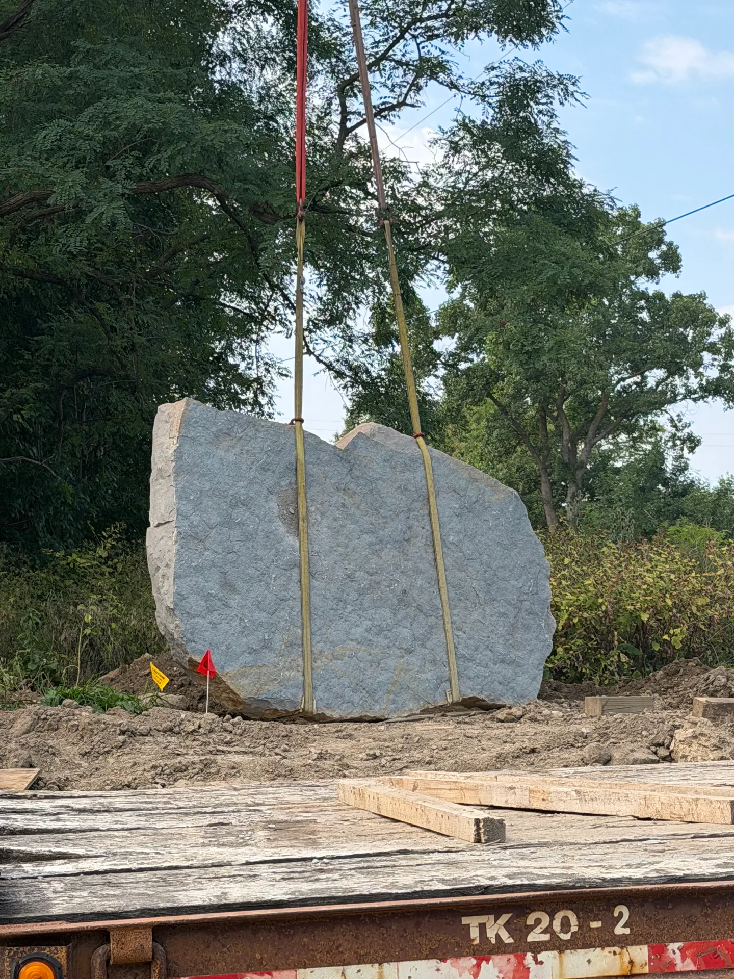 The entrance stone monument set in place at Oaks of Tyrone subdivision awaiting the Oaks of Tyrone name etching, with natural landscaping and wooded backdrop in Tyrone Township Michigan