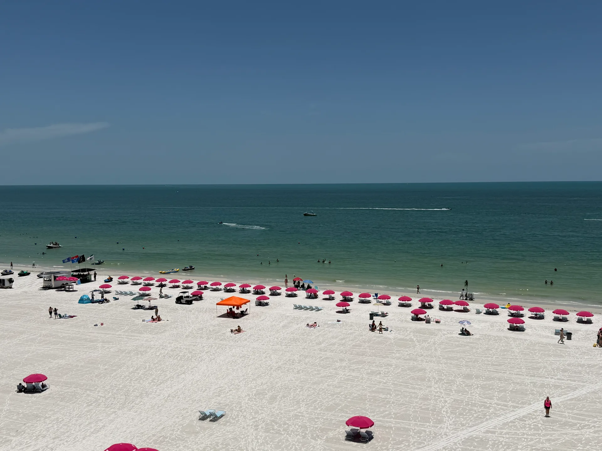 Sunny white-sand beach with pink umbrellas