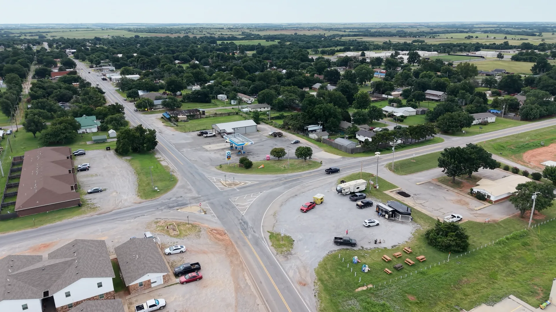 Aerial view of a small-town crossroads in Sterling, Oklahoma with residential housing, trees, and community infrastructure