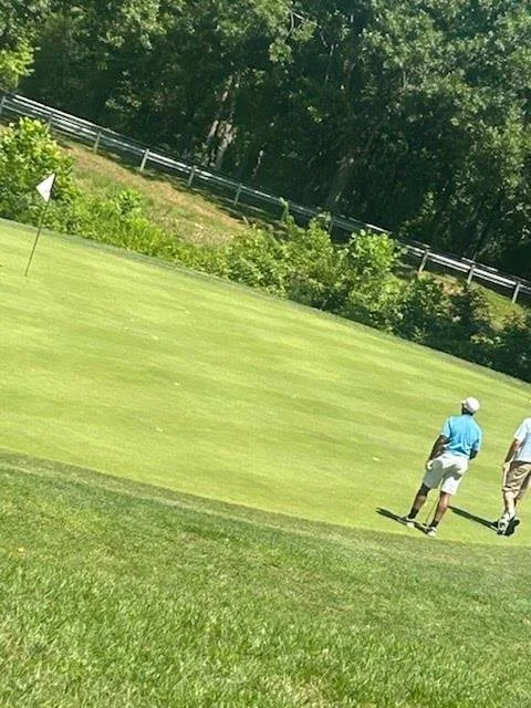 Golfers on the green near the flagstick at the FORE the KIDS Golf Tournament
