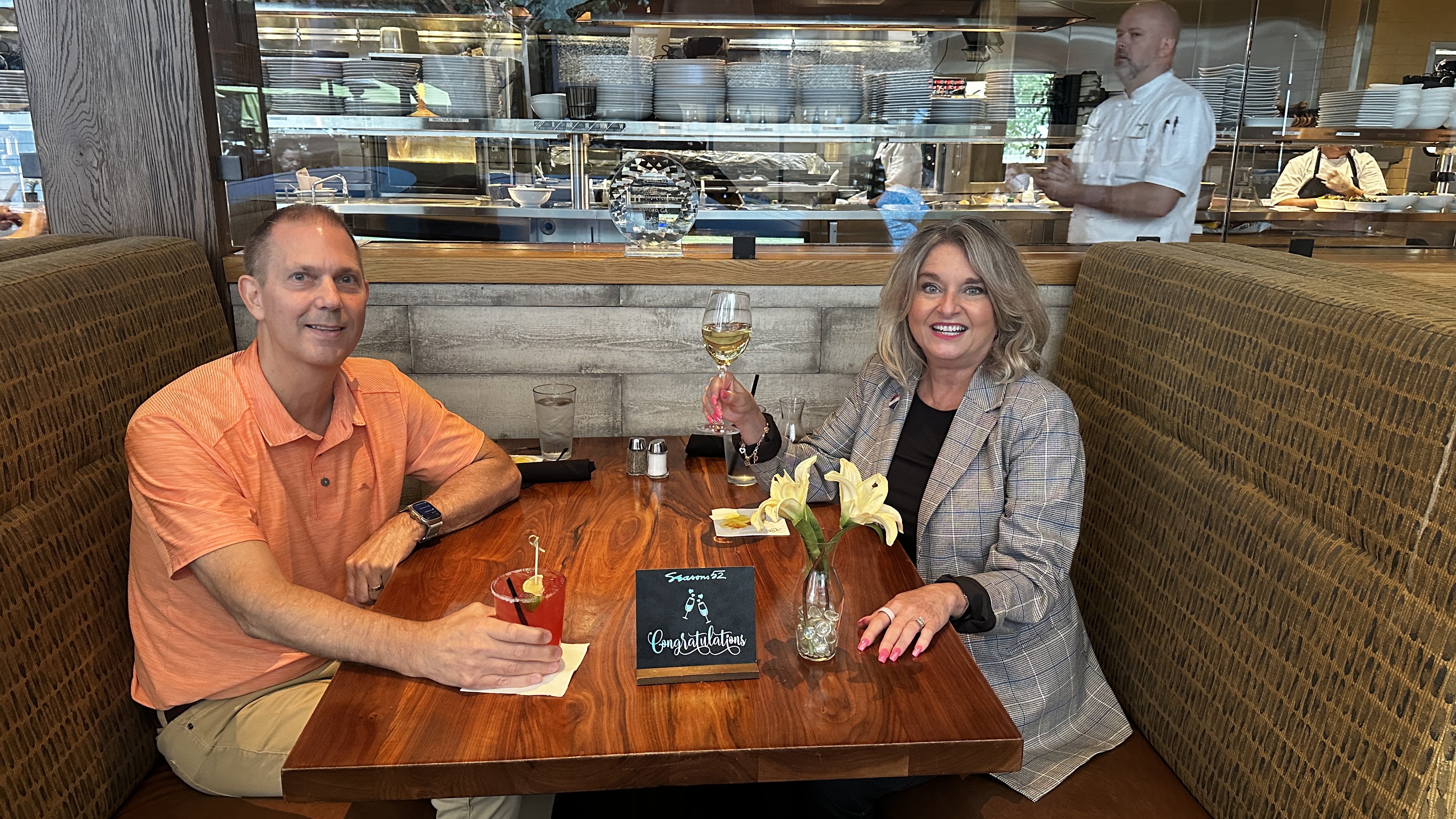 Lisa Harris and Alan celebrating a closing at Seasons 52 restaurant in Buford Georgia with Congratulations sign