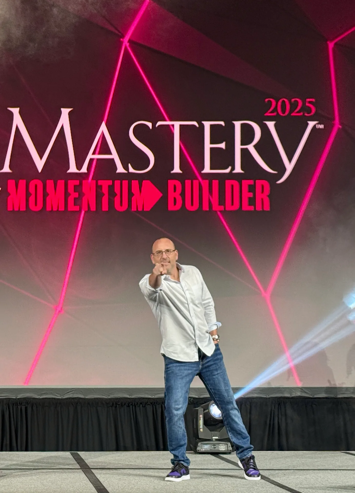 Craig Davis pointing at the camera on stage at Mastery 2025 Momentum Builder