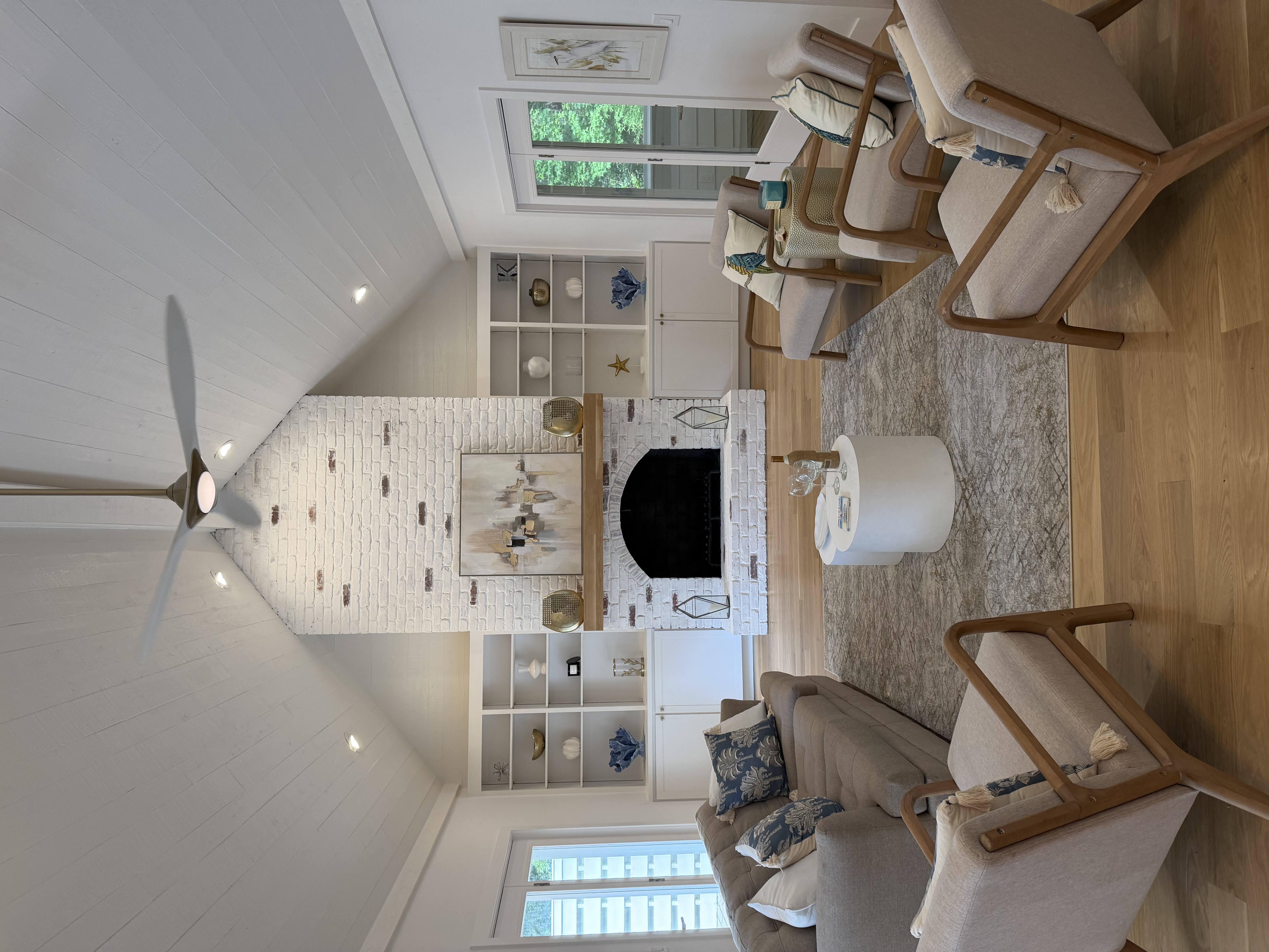 Bright Lowcountry living room with a white fireplace, built-in bookshelves, and light gray seating